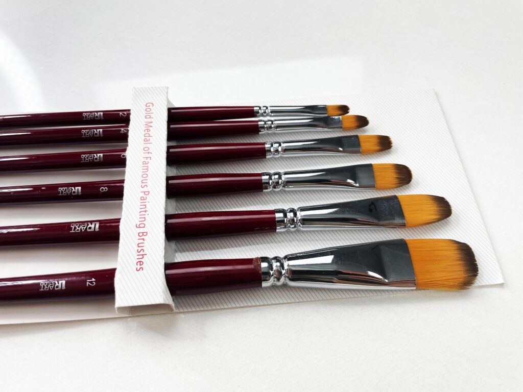 A collection of 6 Filbert paint brushes arranged neatly on a surface