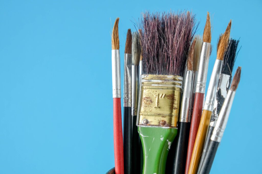 Row of artist paint brushes close up on blue background