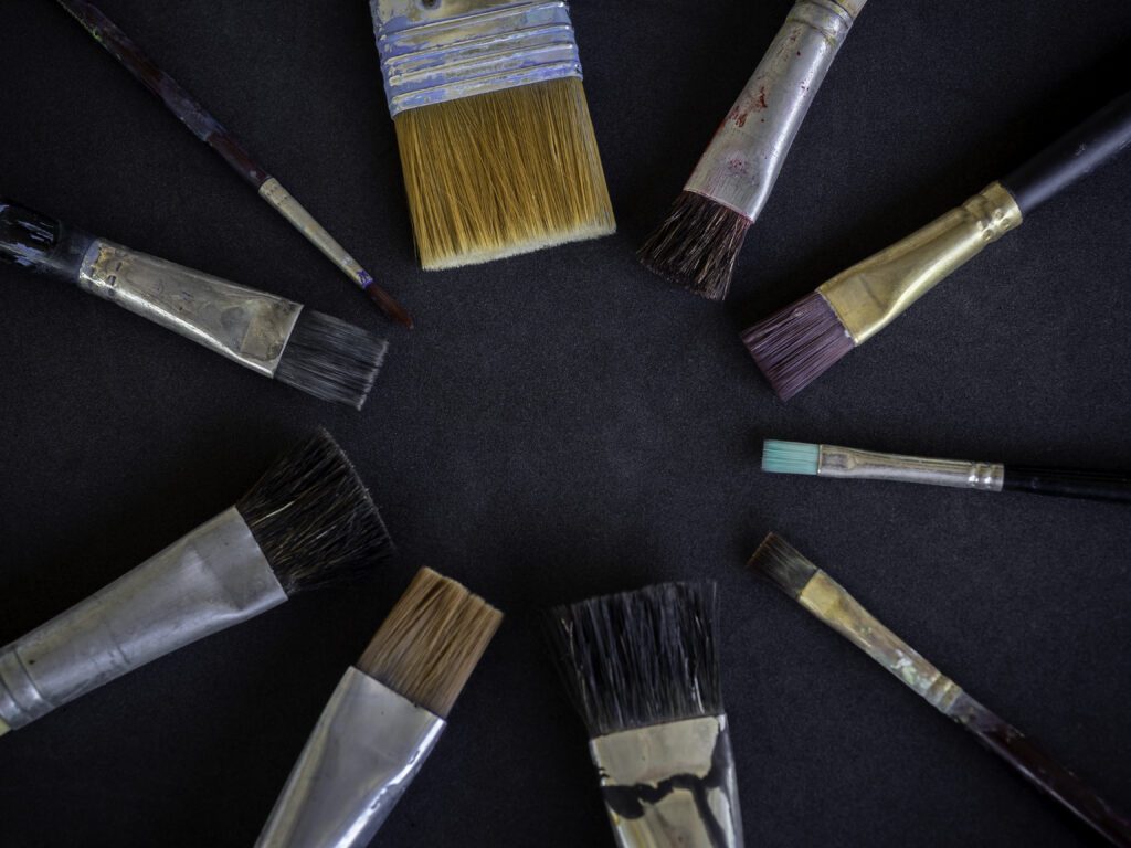 Various used artist paint brushes many size arrange in circle isolated on dark background with copy space.